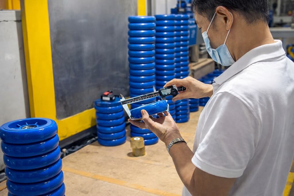 A male quality control inspector is checking the blue wheels