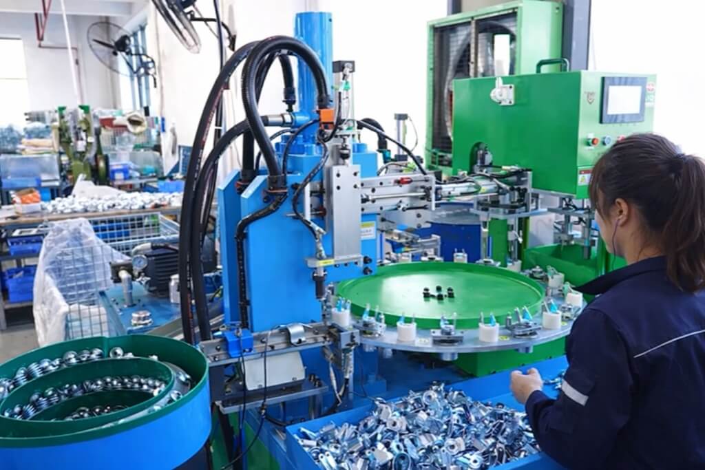 a female worker sitting in front of a caster assembly machine