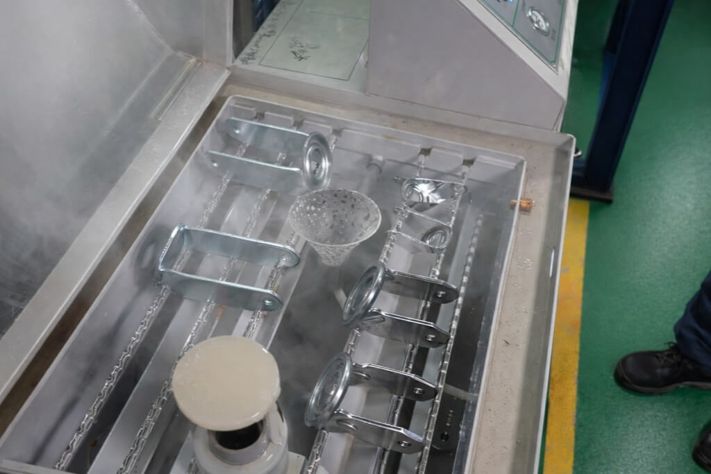 6 caster brackets laying on the rack of a salt spray test machine