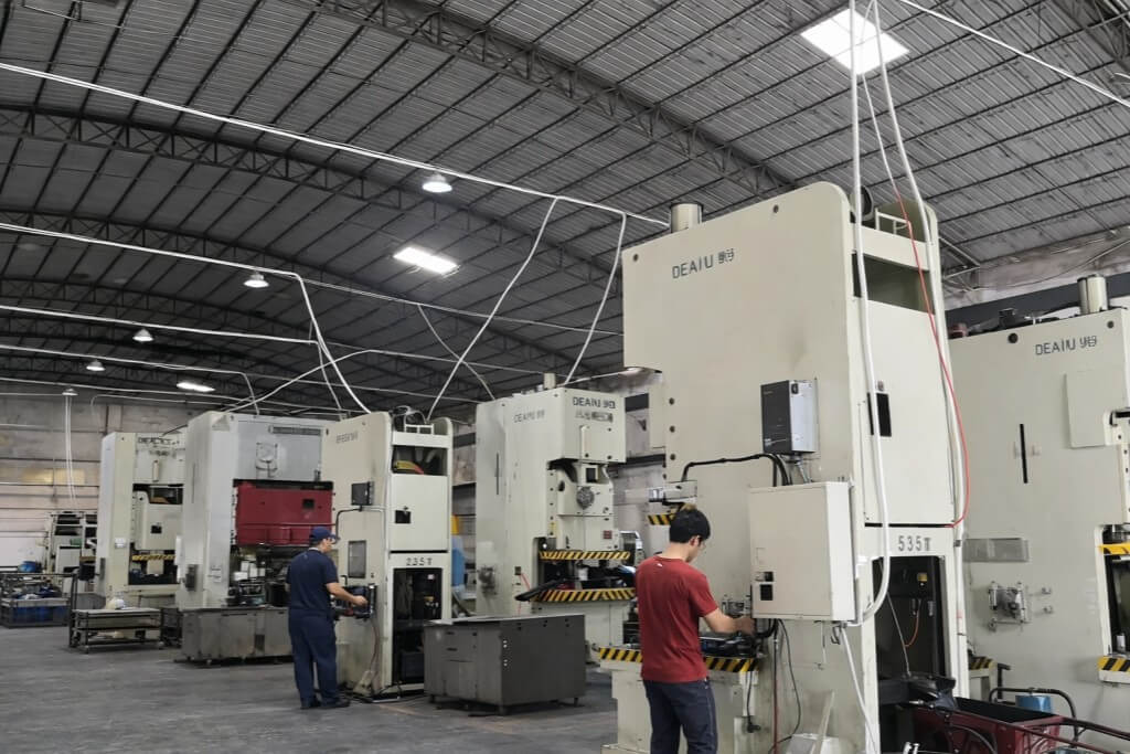 workers operating stamping machines in factory workshop