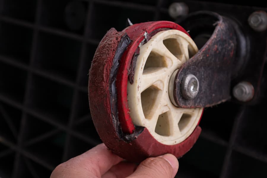 a close-up view of a cracked red polyurethane caster wheel