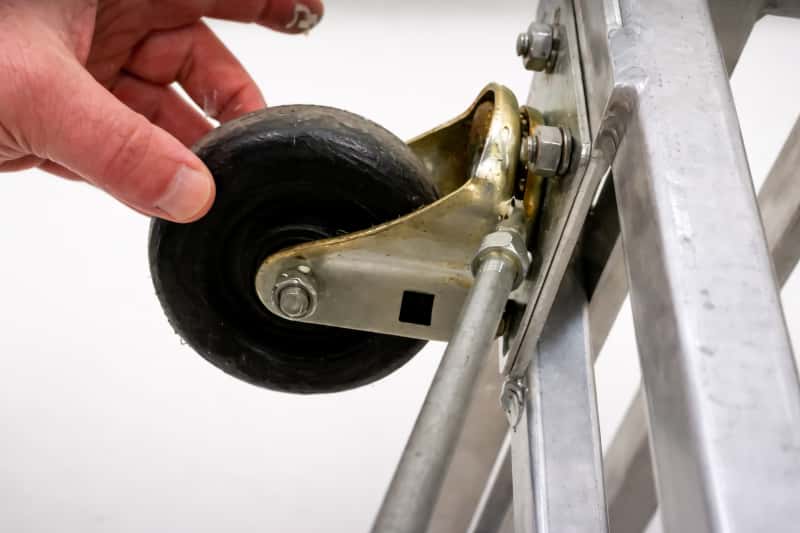 A close up view of a person cleaning and lubricating a caster wheel